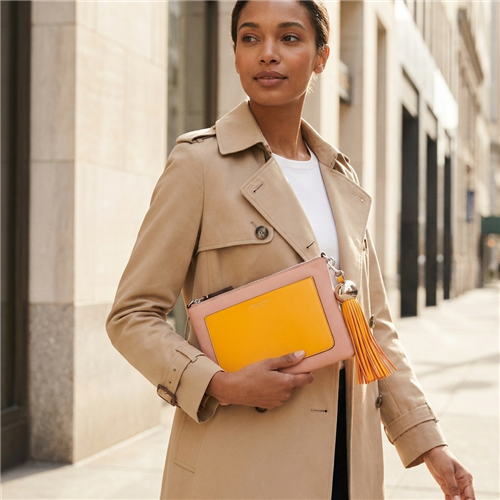 Tory Burch blush pink leather convertible crossbody clutch with marigold yellow front pocket, matching long tassel, slim shoulder strap and polished metal hardware.