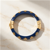 Tory Burch Kira glossy blue resin bangle bracelet with repeating gold tone T logo charms, polished gold hardware, 2.25 inch diameter, and 0.5 inch width.