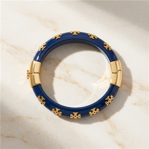 Tory Burch Kira glossy blue resin bangle bracelet with repeating gold tone T logo charms, polished gold hardware, 2.25 inch diameter, and 0.5 inch width.