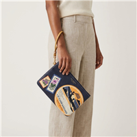 Tory Burch Perry leather wristlet in Royal Navy and Daylily with colorful vintage aviation patches, airplane graphics, floral travel stamps, first cabin baggage artwork, gold tone hardware, and wrist strap.