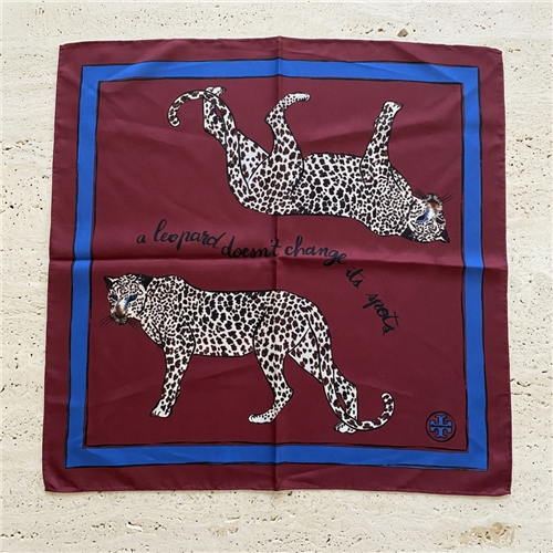 Tory Burch 21 inch burgundy silk square scarf with two black and white spotted leopards, A Leopard Never Changes Its Spots text, blue border, and logo motif.
