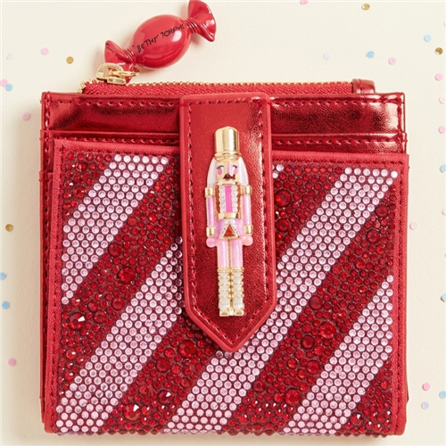 Betsey Johnson Kitchmas Nutcracker metallic red card case wallet featuring red and white rhinestones, dimensional pink and gold tone nutcracker detail, and wrapped candy inspired zipper charm.