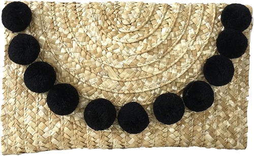 Fashion Culture woven straw envelope clutch in natural straw featuring oversized black pom pom trim, fold over flap closure, lightweight summer design, and a 10 x 6.5 inch silhouette ideal for beach vacations, resort wear, and warm weather occasions.