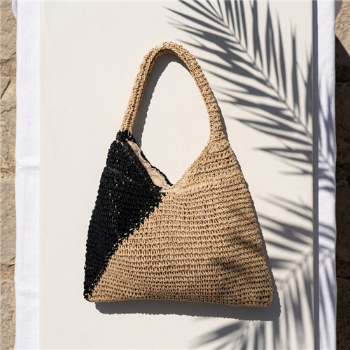 Chic crochet raffia shoulder bag in a natural and black color block design featuring a spacious hobo silhouette with a comfortable shoulder strap for beach vacations, travel, shopping, and everyday summer wear.