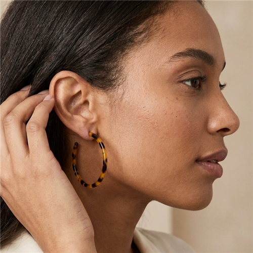 The Bagtique Jewelry Collection Jazlyn  2 inch tortoise shell effect hoop earrings with a slim round silhouette and mottled amber, honey brown, and black pattern.