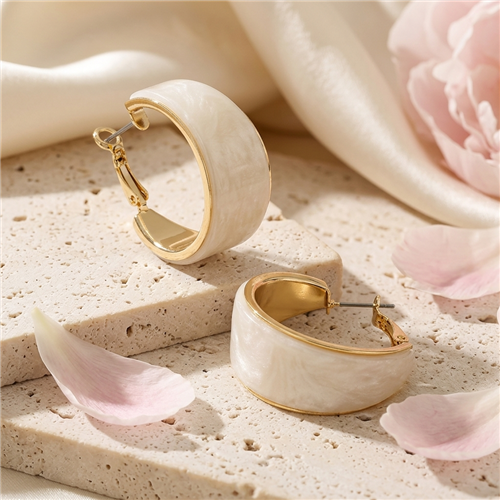 The Bagtique Jewelry Collection wide hoop earrings featuring creamy white acrylic panels framed in polished gold tone metal with a compact chunky curved silhouette.