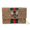 Gold multi mini clutch crossbody bag with a beaded front, dimensional black and white bee motif, green and red vertical stripes, foldover silhouette, and removable gold tone chain strap.